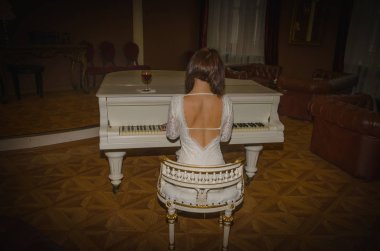 piyanoda beyaz bir elbise bir bardak şarap yasal yanında bir kız oturur