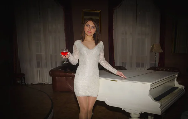 No átrio perto da menina piano em um vestido branco com um copo de vinho — Fotografia de Stock