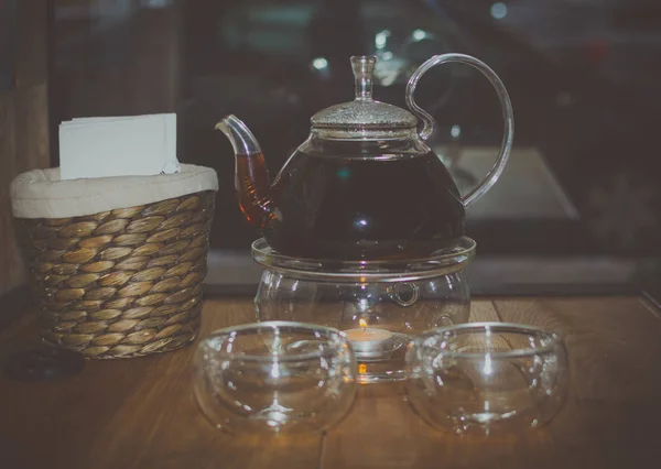 На столе две прозрачные чашки чая и чайник нагревается на свече — стоковое фото