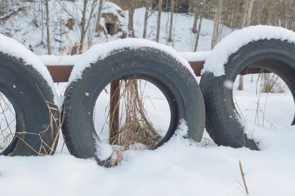 Gamla däck som stängsel av vägen på vintern — Stockfoto