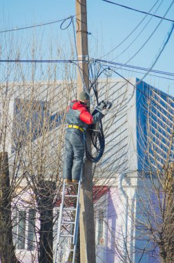 Tel sokak kutup ayakta merdivenlerde işçi elektrikçi onarır.