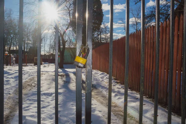 Um portão de barras de ferro na neve, em bom tempo — Fotografia de Stock