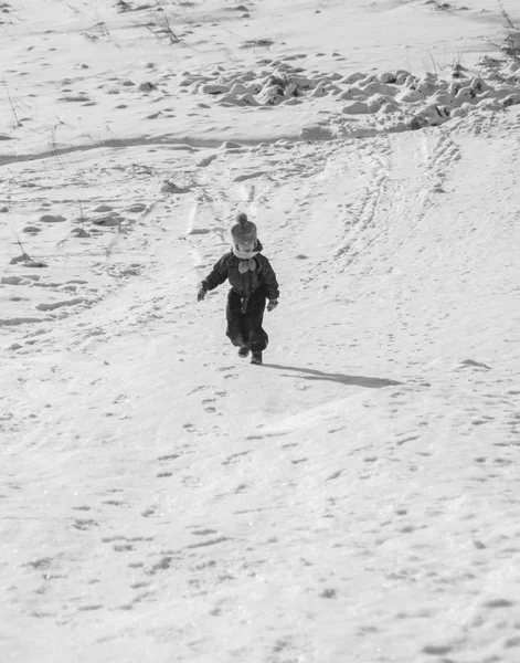 Ett barn går på snö rutsch banorna, svart och vitt. — Stockfoto