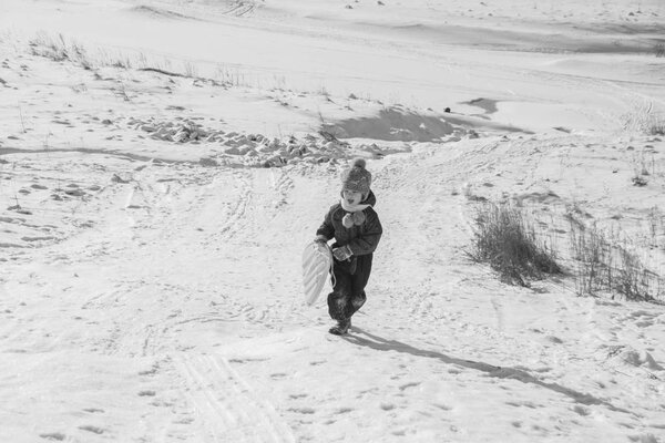 черно-белый, счастливый ребенок на холме зимой
