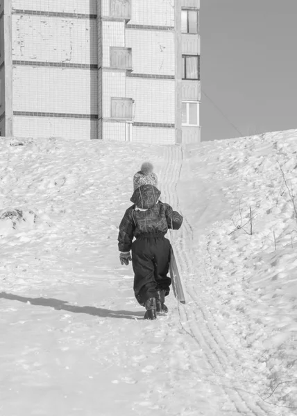 Por trás, a criança passa por escorregas de neve, preto e branco — Fotografia de Stock