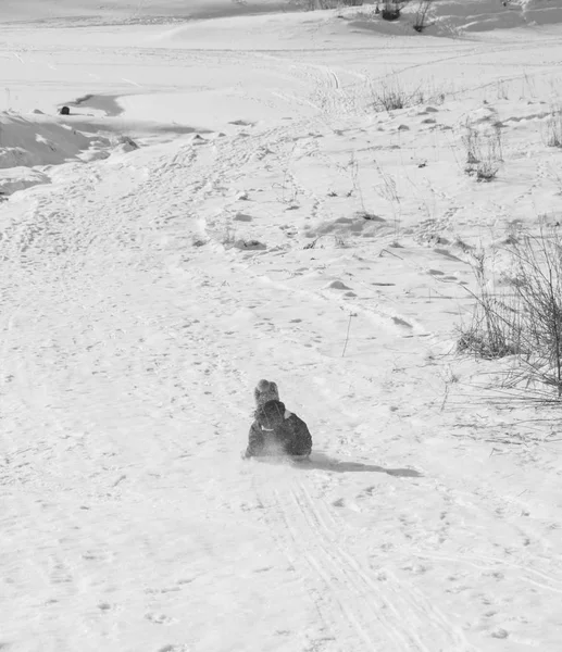 No inverno, a criança montando as colinas em trenós, preto e branco . — Fotografia de Stock