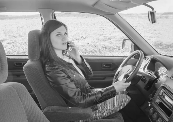 Hermosa chica hablando por teléfono sentado en el coche, negro y — Foto de Stock