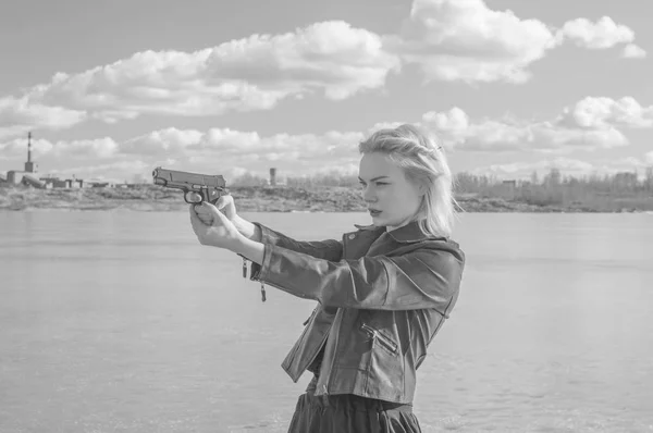 Svart och vitt, flicka som syftar till en pistol på bakgrunden av l — Stockfoto