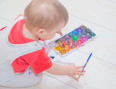 bir fırça ve suluboya ile oturan kirli çocuk.