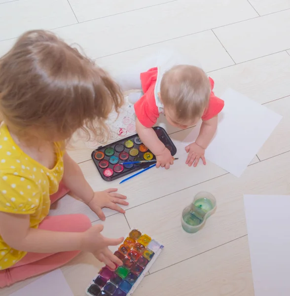 Due bambini seduti sul pavimento disegnando con acquerelli . — Foto Stock