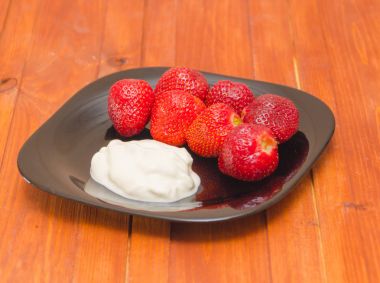 ahşap bir masa üzerinde bir kase çilekli dondurma.