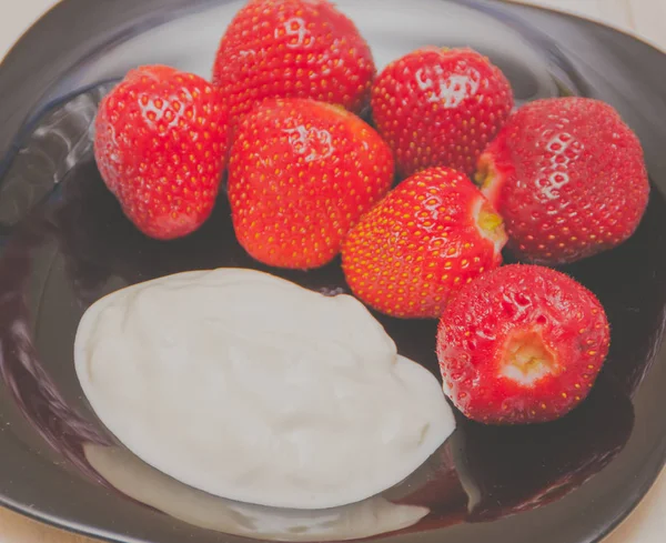 On the table a plate with strawberries and sour cream, close-up. — Stock Photo, Image