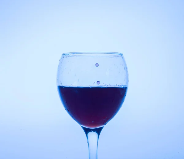Zvýrazněno modrou sklenici červeného vína s kapkami. — Stock fotografie