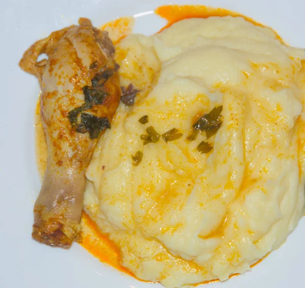 kızarmış tavuk budu ile bir beyaz tabak püresi patates.