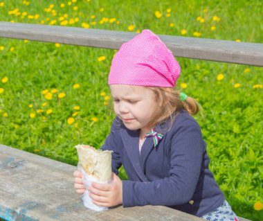 güneşli bir sokakta, lokanta çocuk yiyor.