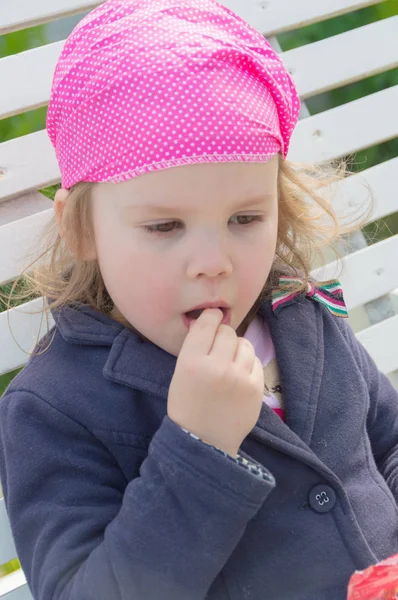 Bir çocuk bir salıncak üzerinde oturan şeker yiyor. — Stok fotoğraf