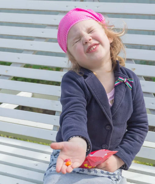 Zittend op de schommel kind is gulzig voor candy. — Stockfoto