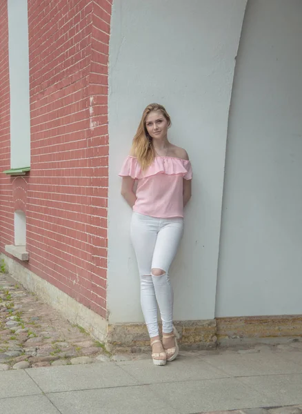 Ceglany mur atrakcyjna dziewczyna w różowa bluzka. — Zdjęcie stockowe