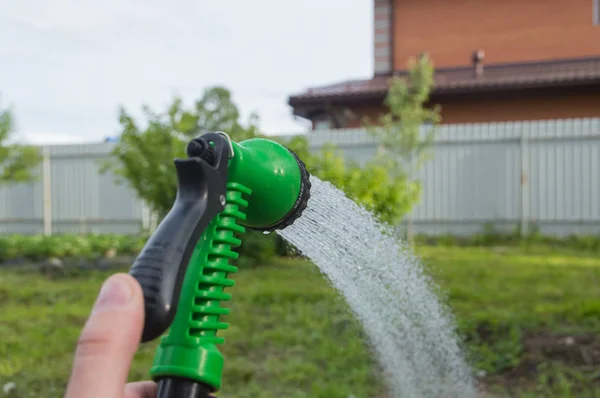 Innaffiamento del bambino con un tubo da giardino . — Foto Stock