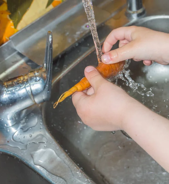 มือของเด็กในครัวล้างแครอท . — ภาพถ่ายสต็อก