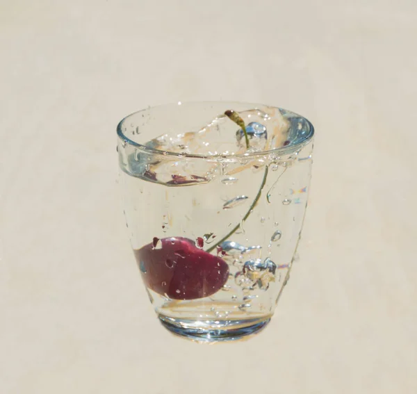 Cherry and splash in the clear glass of water . — стоковое фото