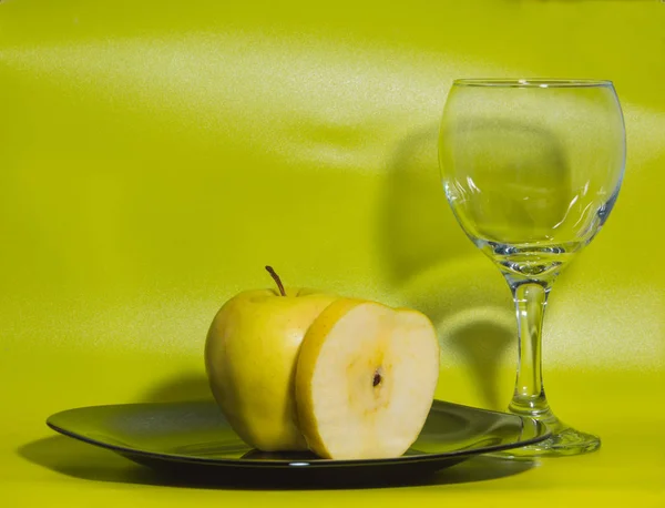 Un bicchiere d'acqua e mela gialla su piatto su fondo verde . — Foto Stock
