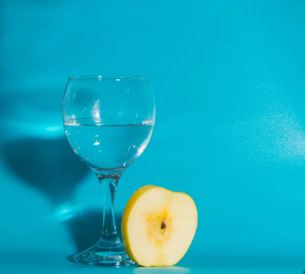 On a blue background and a slice of yellow Apple with a glass of — Stock Photo, Image