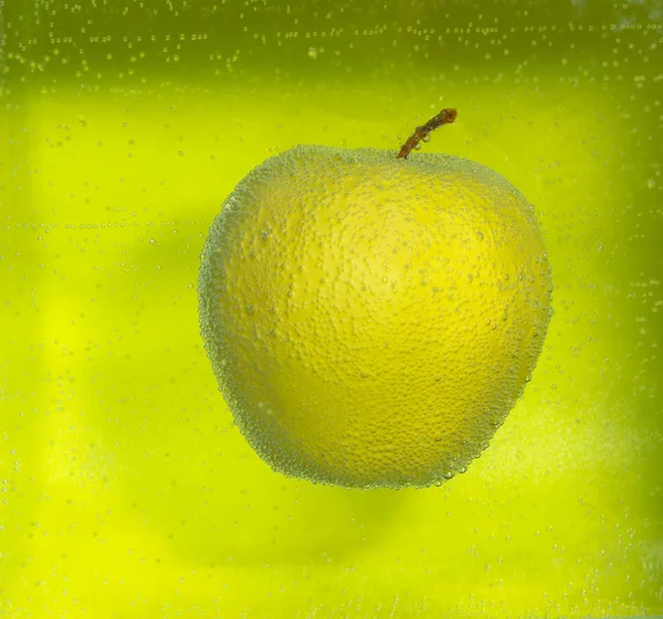 Su sfondo verde mela gialla nelle bolle . — Foto Stock