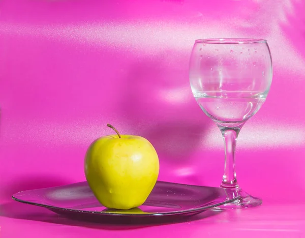 Su fondo rosa sul piatto mela gialla con un bicchiere di w — Foto Stock