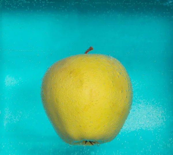 La mela nelle bolle d'aria su uno sfondo blu . — Foto Stock