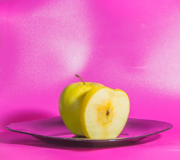 Il piatto una Mela gialla su uno sfondo rosa . — Foto Stock
