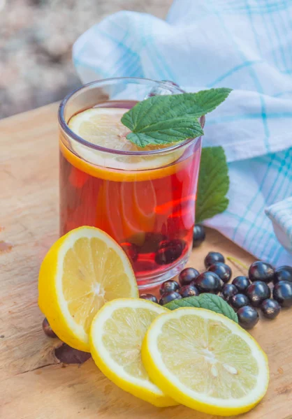 Auf einem Holztisch kühles Kompott mit Zitrone und Beeren, schwarzer Curry — Stockfoto