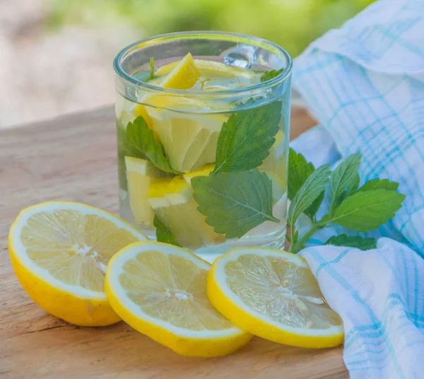 Su un tavolo di legno bevanda estiva è l'acqua con menta e limone . — Foto Stock