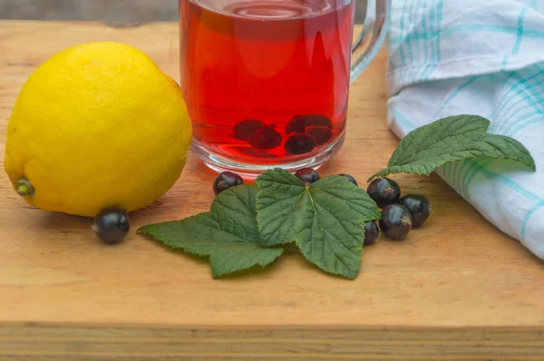 Auf einem Holztisch Tee schwarze Johannisbeere mit Zitrone. — Stockfoto