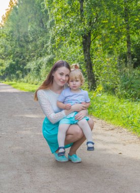 çocuk anne yolda kucağına oturur.
