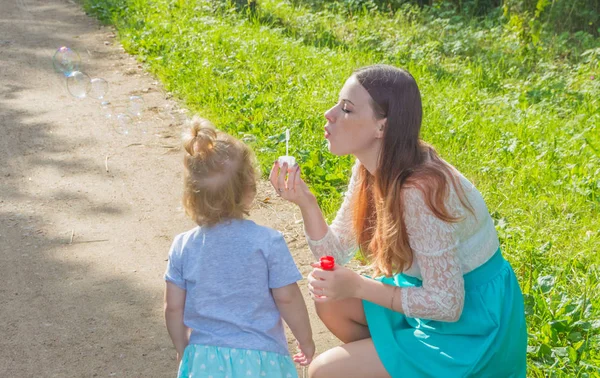 Çocuk annesiyle kabarcıklar parkta üfleme. — Stok fotoğraf