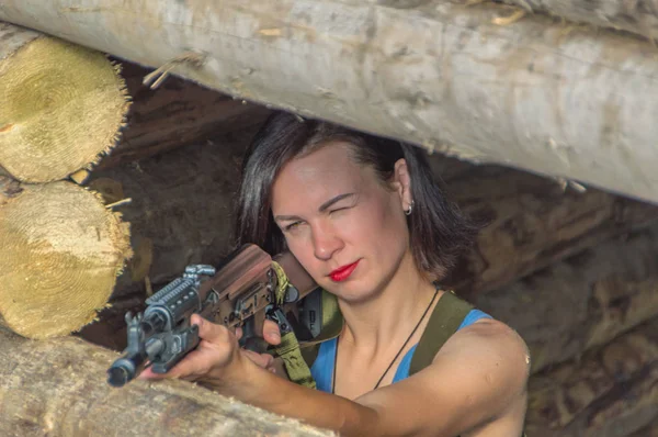 Närbild av en flicka med en pistol i en trä defensiv täcka. — Stockfoto