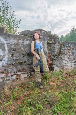 taş duvar, silahlı bir kız ayakta poz.