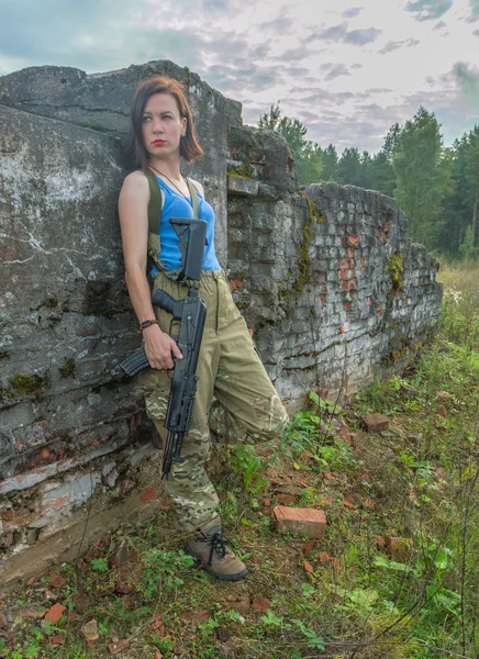 Flicka med pistol poserar i en stenmur. — Stockfoto