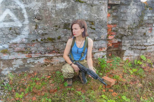 Posant tout en étant assis à un mur de béton la fille avec l'arme — Photo