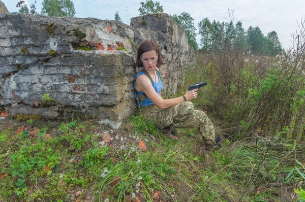 La fille avec un pistolet caché derrière un mur de béton . — Photo