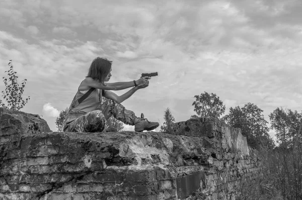 Blanco y negro, en la pistola de las manos de la chica, ella se sienta en una roca . — Foto de Stock