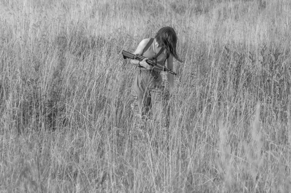 Preto e branco, nas mãos da menina a arma está no prado — Fotografia de Stock