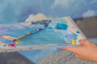 boyalar ve sanatçının ellerinde fırçalar paleti 