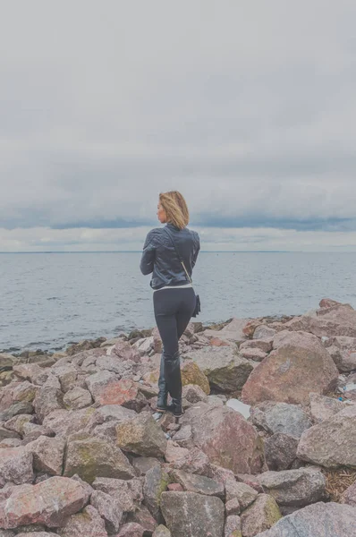 Chica atractiva de pie en una playa rocosa en un día nublado — Foto de Stock