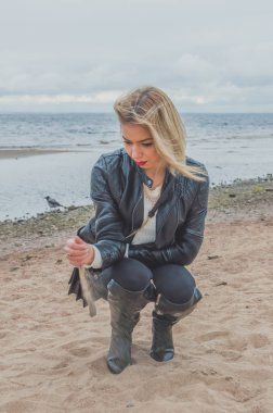 Bulutlu gün güzel bir kız bir kumsalda yürür.