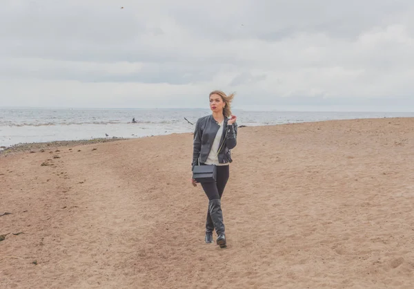 Bulutlu gün çekici bir kız sahilde yürüyor.