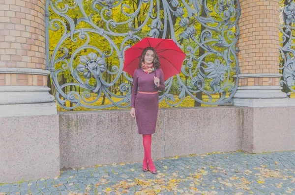 W pobliżu kutego żelaza płot dziewczyna z parasolem jesienią — Zdjęcie stockowe