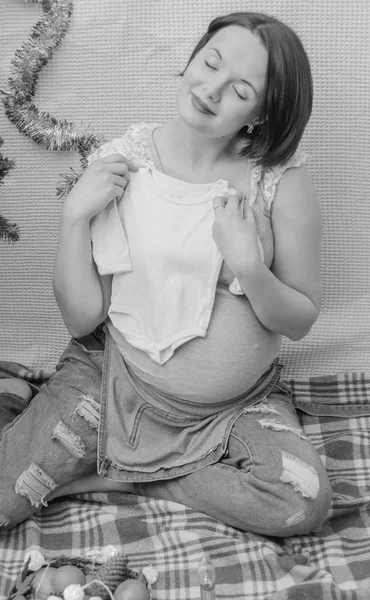 Met kinderkleding in zijn handen, zwangere meisje — Stockfoto