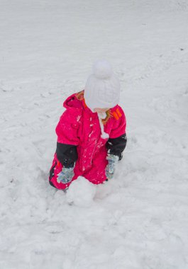 bir kız oyun alanında bir kardan adam kışın sculpts.